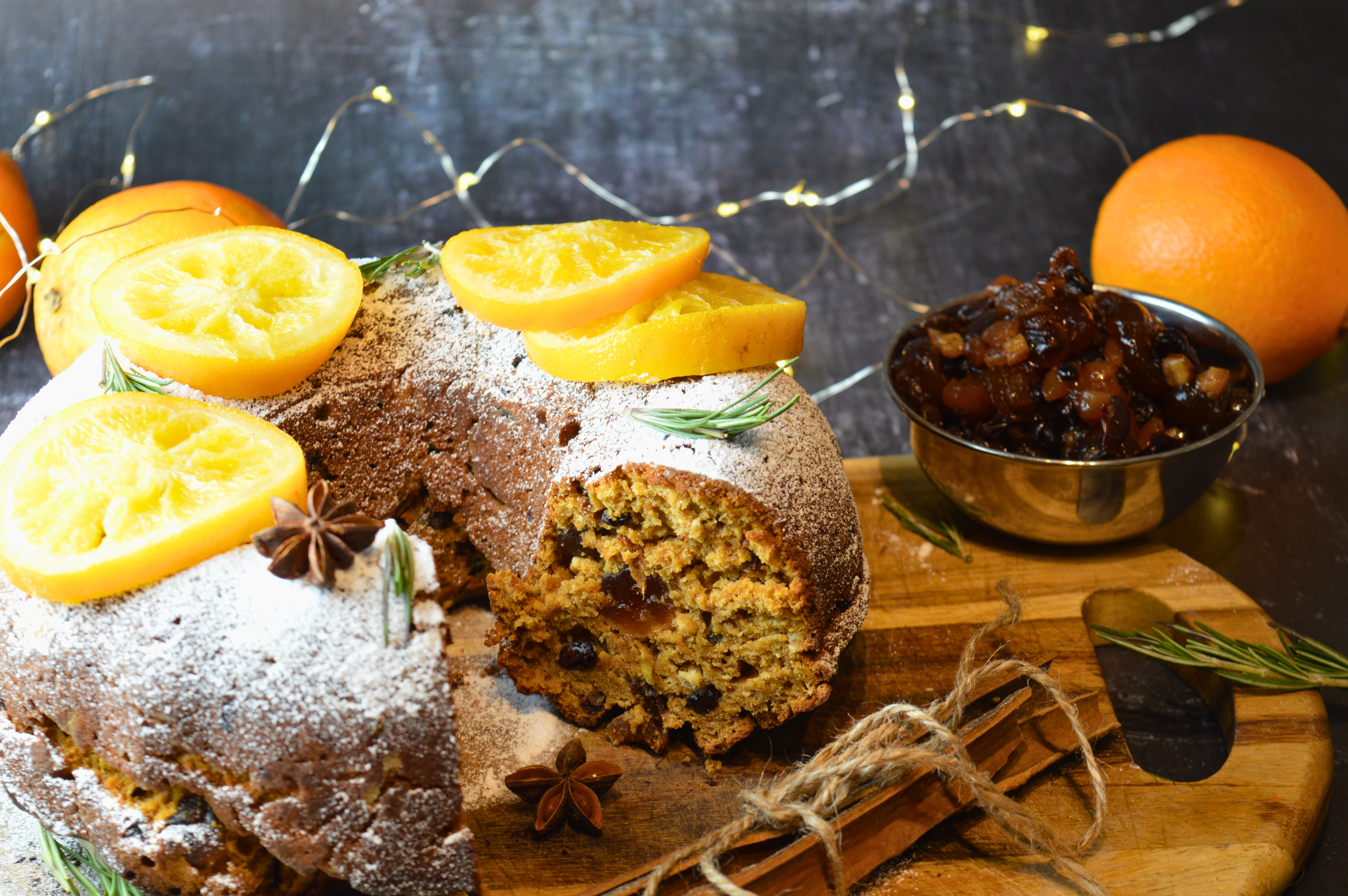 Mince Pie Bundt Cake with Orange and Amaretto Glaze, Garnished with Powdered Sugar and Candied Orange Slices on a Festive Table